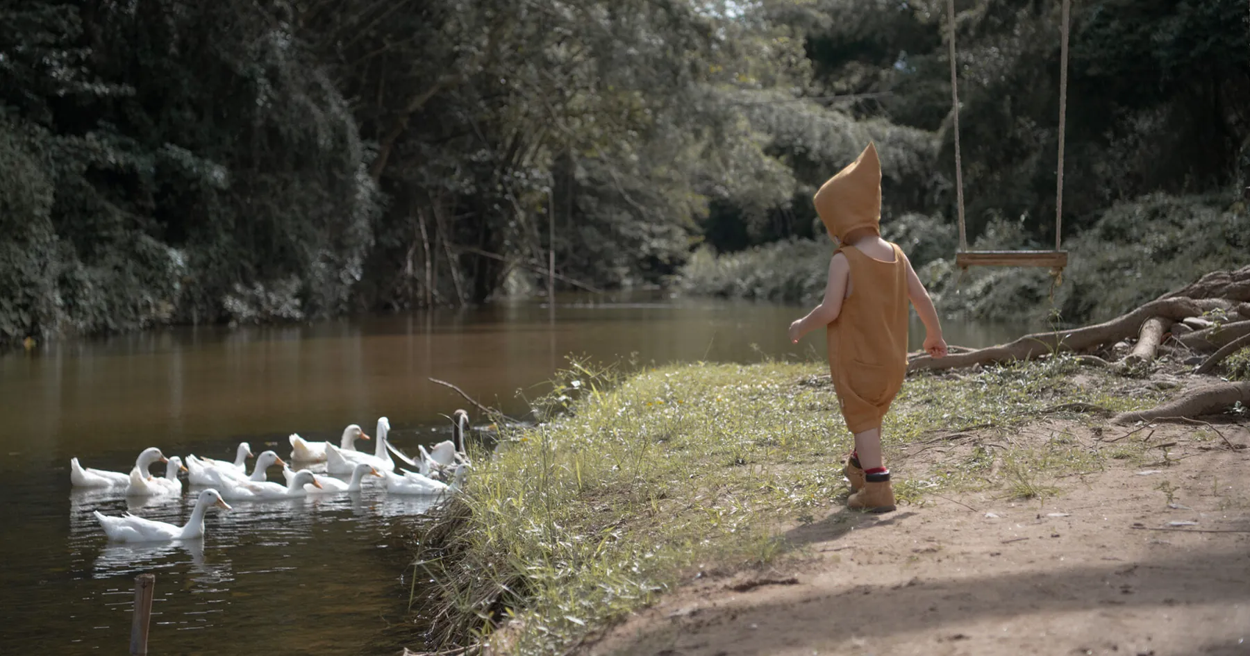 Child by a pond wearing the Little Wanderer collection